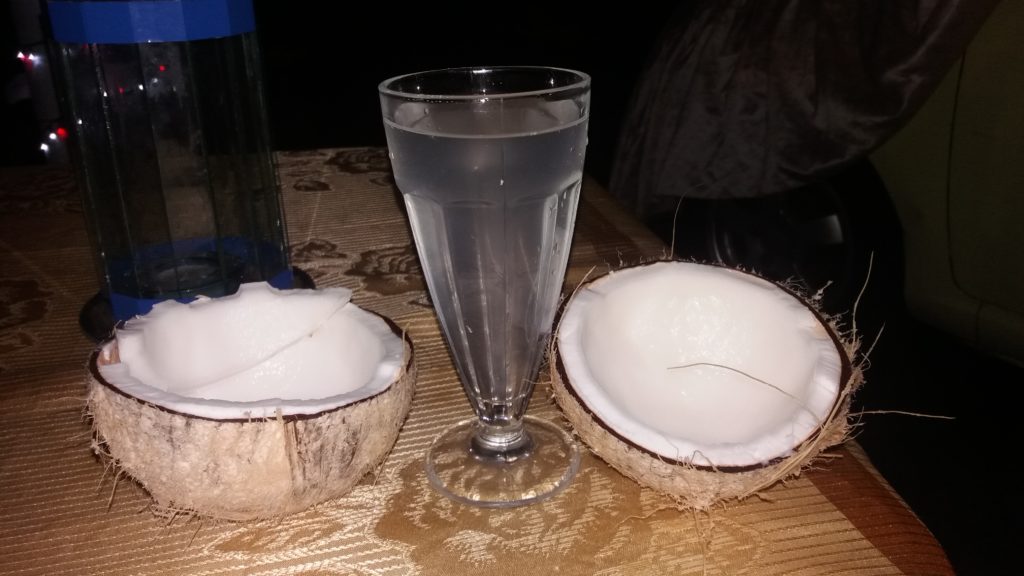 Rozseknutý čerstvý kokosový ořech s kokosovou vodou ve sklenici.